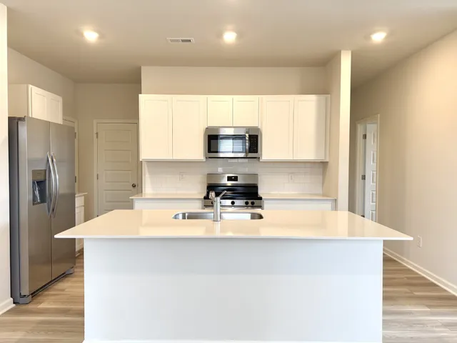 a kitchen with kitchen island a stove a sink and a refrigerator