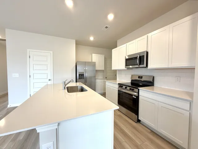 a kitchen with kitchen island a sink stainless steel appliances and cabinets