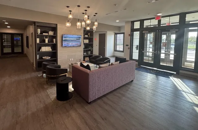 a living room with furniture wooden floor and large windows
