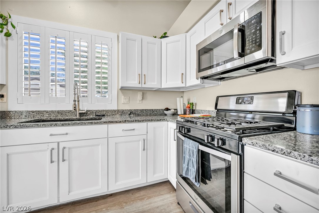 1234 Sunfire Street Henderson, NV 89014 - Photo 11 of 40 A well-appointed kitchen features crisp white cabinetry, granite countertops, and modern stainless steel appliances.