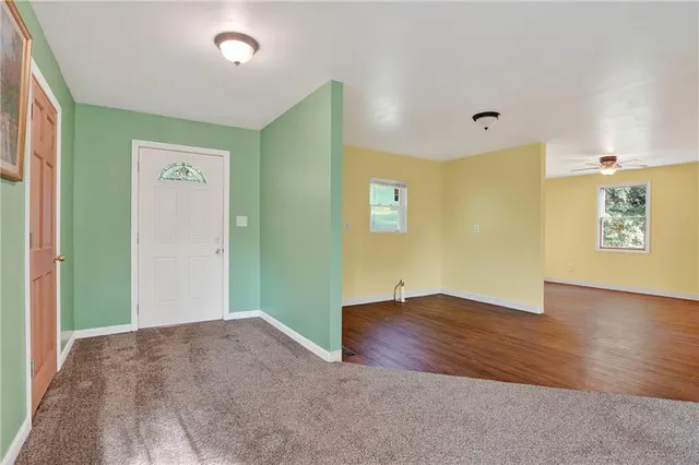 a view of an empty room with window and wooden floor