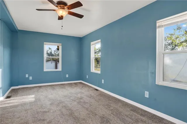 an empty room with windows and fan