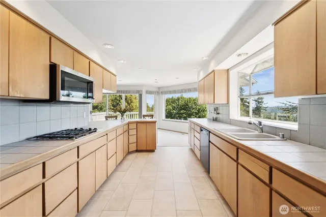 a large kitchen with stainless steel appliances granite countertop a sink and cabinets
