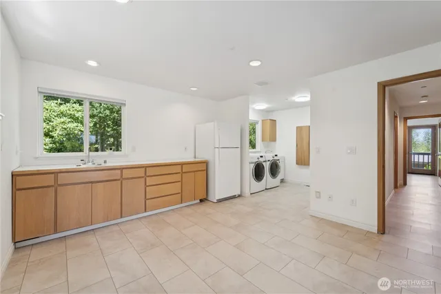 a large white kitchen with a sink and dishwasher a oven with white cabinets