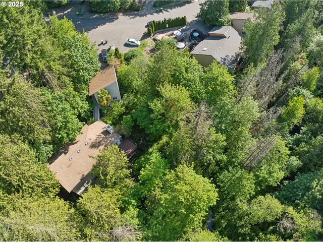an aerial view of residential house with outdoor space and trees all around
