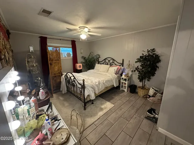 a bedroom with a bed table flowerpot and window
