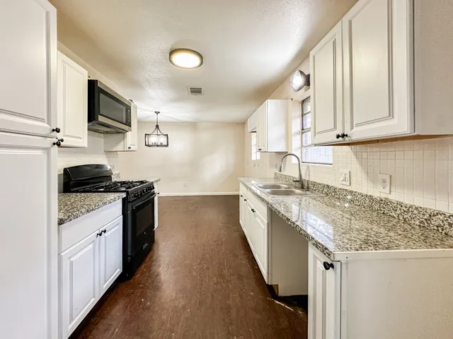 a kitchen with stainless steel appliances granite countertop a sink stove and microwave