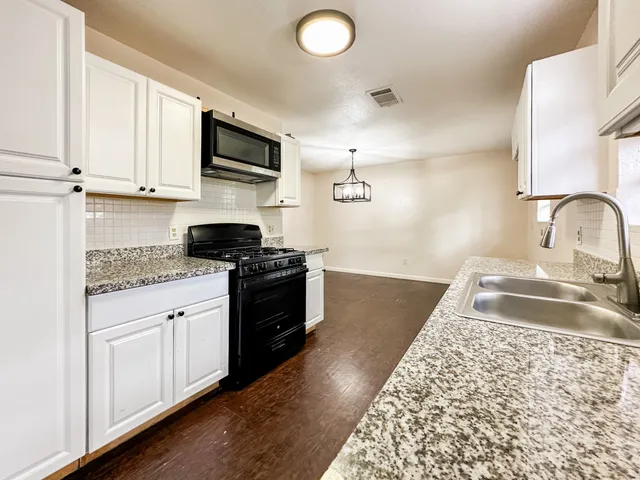 a kitchen with granite countertop a sink stainless steel appliances and cabinets