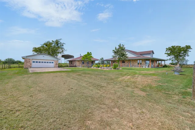 a view of a big house with a big yard and large trees