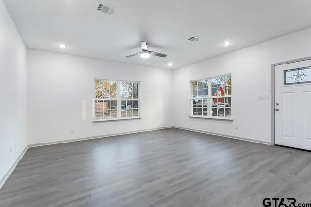 a view of an empty room with wooden floor and a window