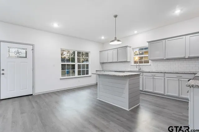 a kitchen with granite countertop wooden floors appliances and cabinets