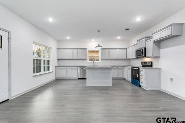 a large kitchen with stainless steel appliances refrigerator a microwave oven and a stove next to a large window