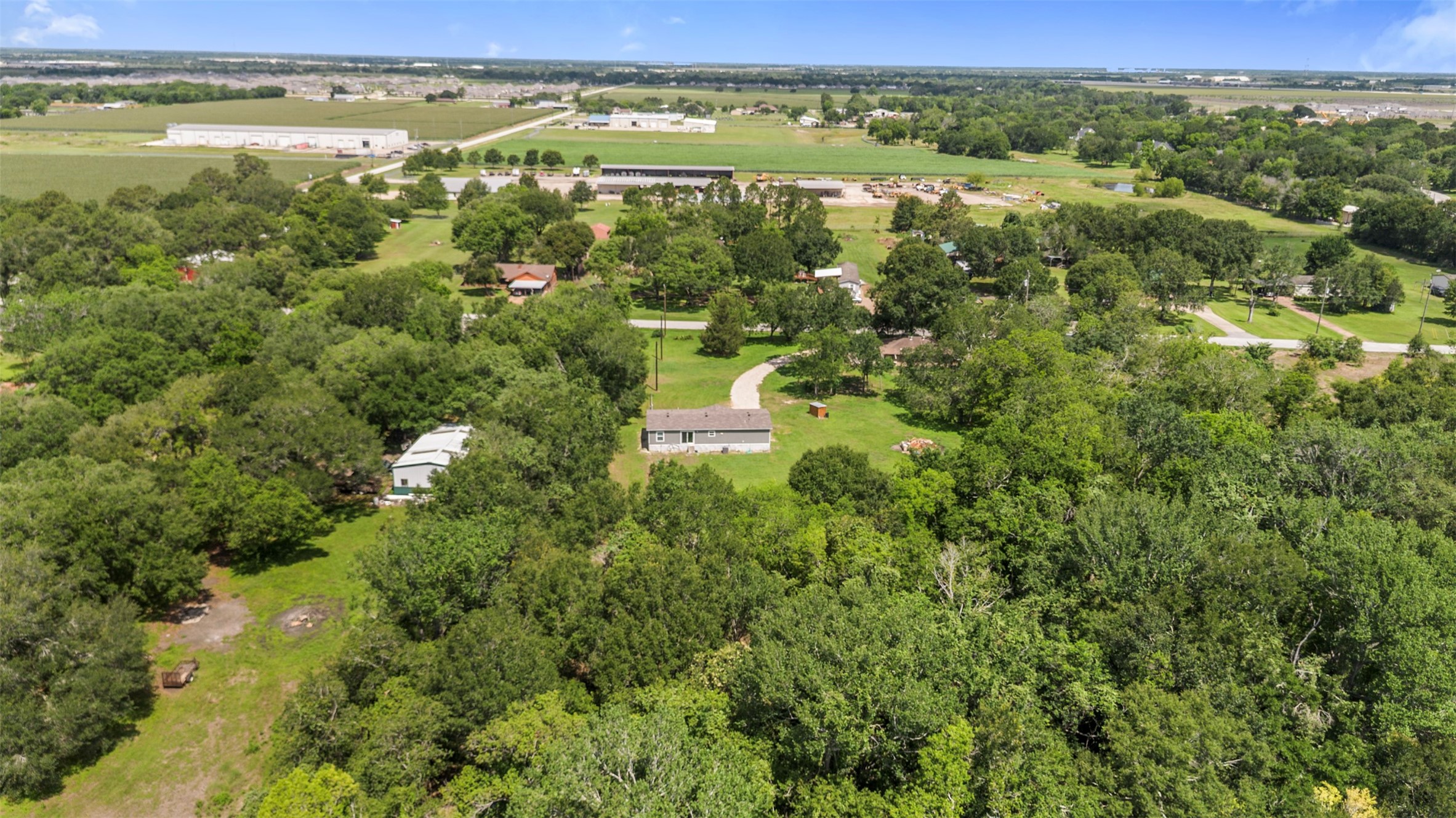 2701 Mazen Road Rosenberg, TX 77471 - Photo 6 of 10 This aerial photo showcases a spacious property surrounded by lush greenery, providing a serene and private setting. The house is centrally located with a curved driveway, and nearby structures are visible, offering a balance of seclusion and community access. Ideal for those seeking a peaceful retreat with ample outdoor space.