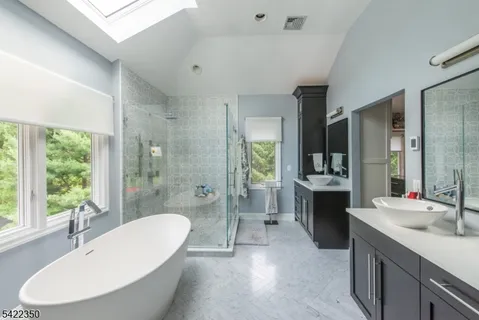 a bathroom with a granite countertop tub sink and mirror