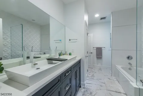 a bathroom with a sink double vanity granite tub shower and a mirror