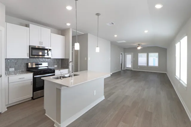 a kitchen with kitchen island white cabinets appliances and a sink