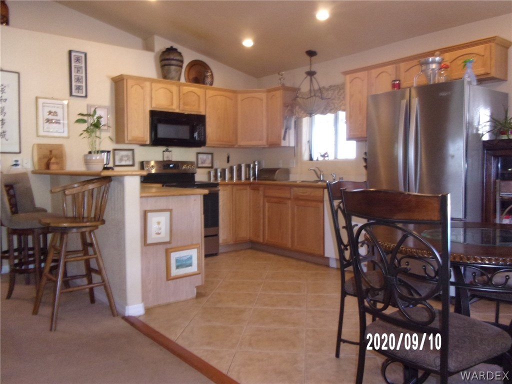 303 Bouse Road Golden Valley, AZ 86413 - Photo 18 of 42 a kitchen with stainless steel appliances granite countertop a refrigerator a stove a sink a dining table and chairs