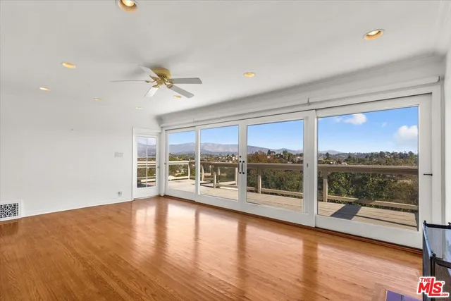 an empty room with wooden floor and natural light
