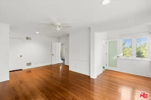 an empty room with wooden floor fan and windows
