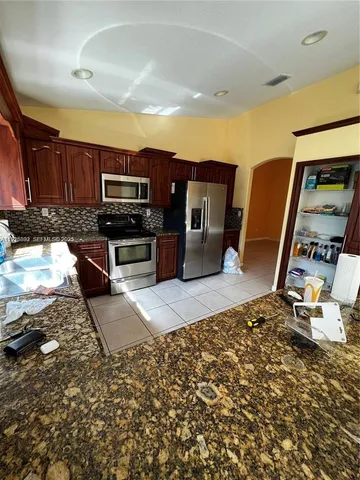 a kitchen with stainless steel appliances a stove a sink a microwave a refrigerator and cabinets