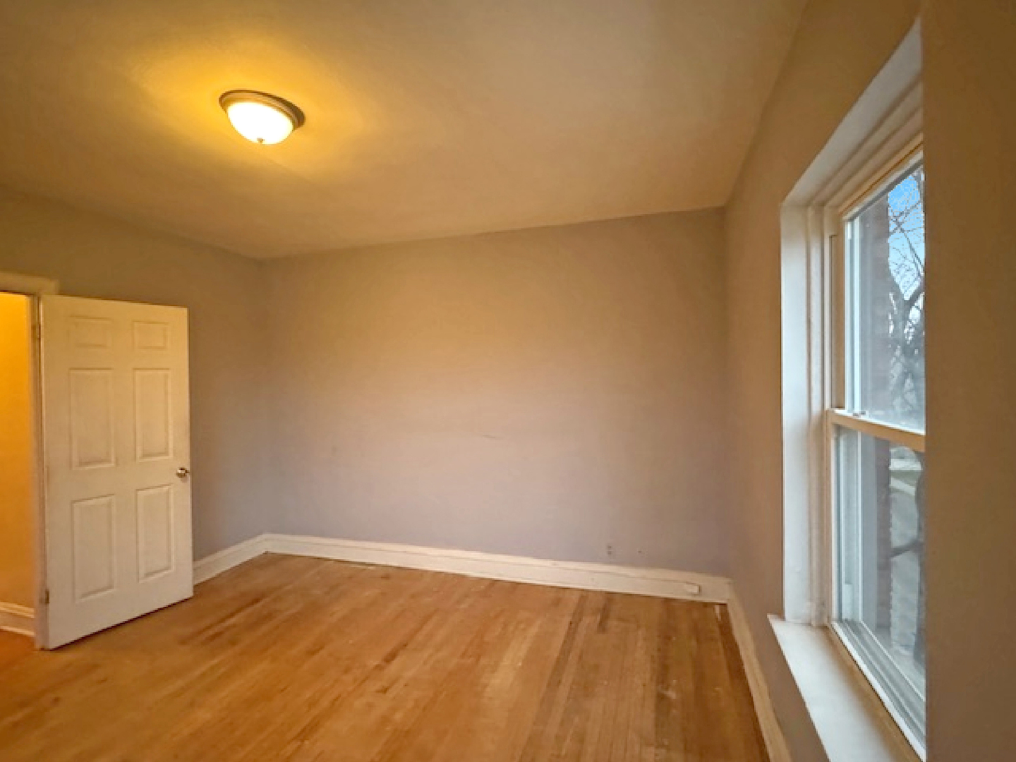 2425 West Pratt Boulevard, Unit 3I Chicago, IL 60645 - Photo 9 of 16 a view of an empty room with wooden floor and a window