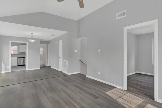 a view of a room with wooden floor empty shelves and a window