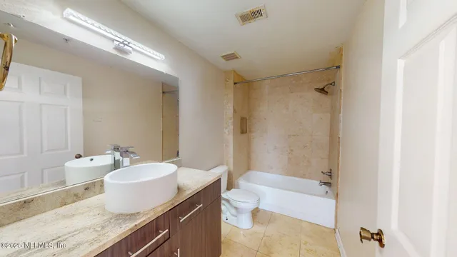 a bathroom with a granite countertop sink a mirror and a bathtub