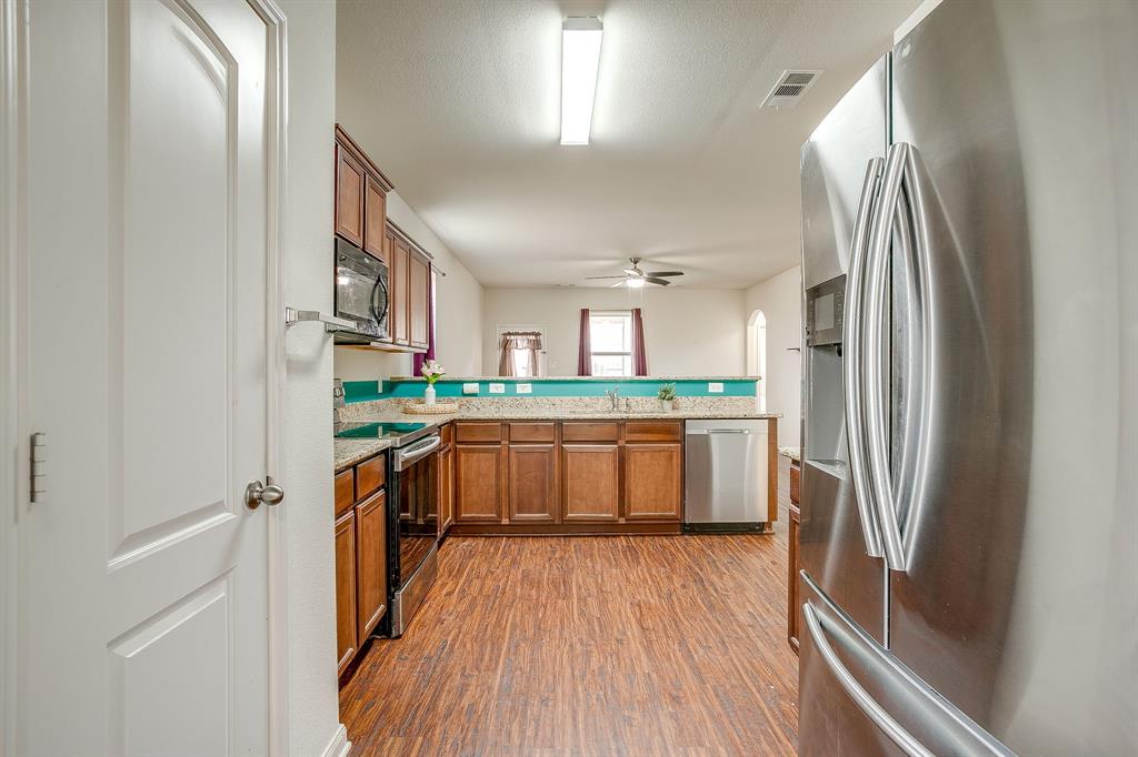 136 Kennedy Drive Venus, TX 76084 - Photo 2 of 27 a kitchen with stainless steel appliances granite countertop a refrigerator a sink dishwasher a stove and white countertops with wooden floor