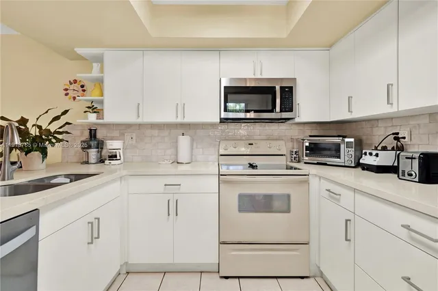 a kitchen with white cabinets and white appliances