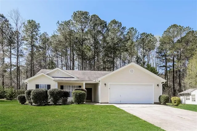 a front view of a house with a garden and trees