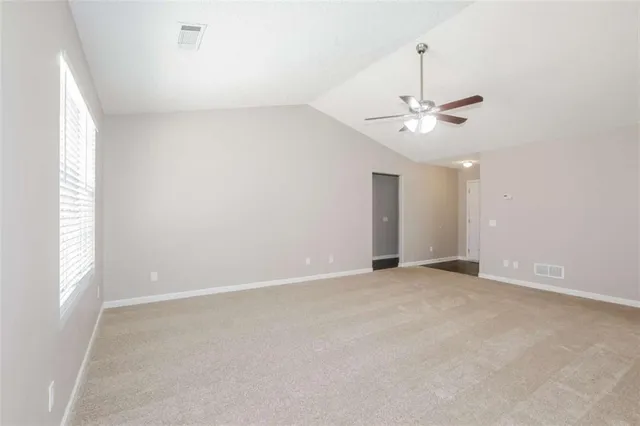 an empty room with a chandelier fan and windows