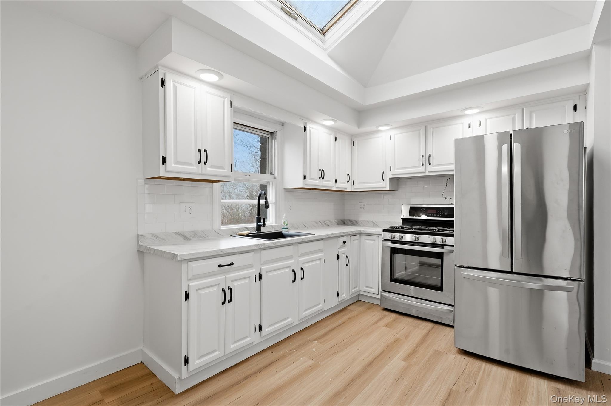 384 Tempaloni Road Ellenville, NY 12428 - Photo 6 of 18 a kitchen with stainless steel appliances white cabinets and wooden floors