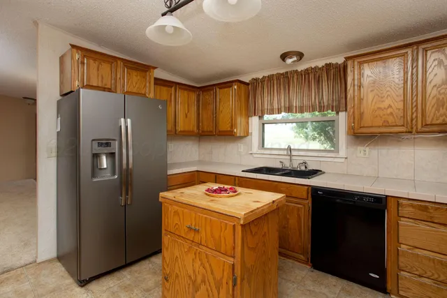 a kitchen with stainless steel appliances granite countertop a refrigerator a sink and a stove