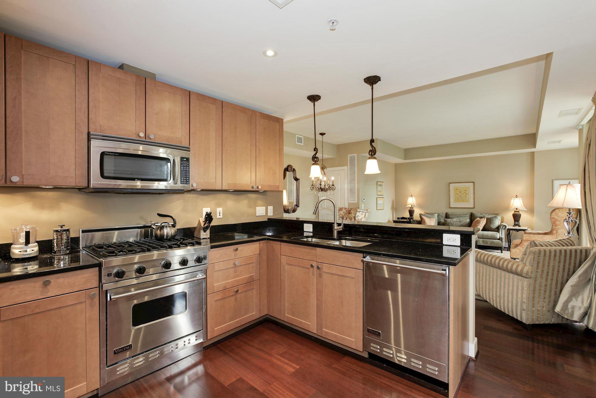 2425 L Street Northwest, Unit 412 Washington, DC 20037 - Photo 9 of 28 a kitchen with kitchen island granite countertop a sink cabinets and stainless steel appliances