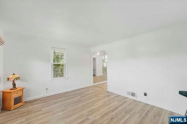 a view of an empty room with a window and wooden floor