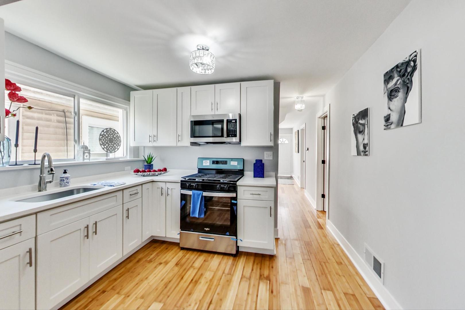 7640 West 63rd Place Summit, IL 60501 - Photo 7 of 29 a kitchen with stainless steel appliances granite countertop a refrigerator a sink dishwasher a stove top oven a refrigerator with wooden floor