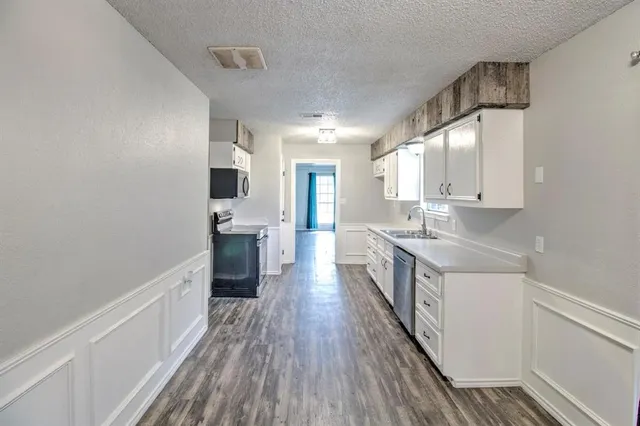a kitchen with a sink and wooden floor