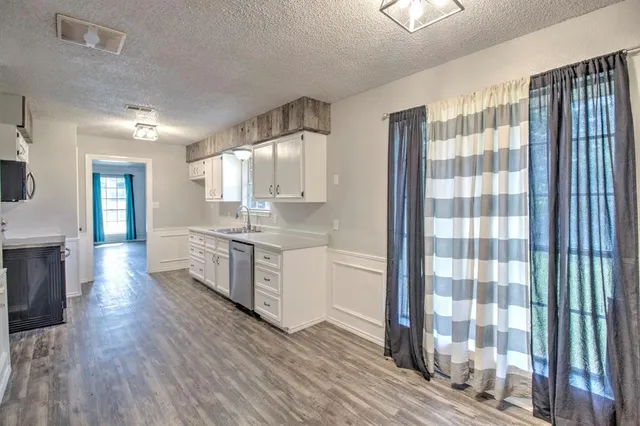 a large kitchen with a lot of counter space and wooden floor