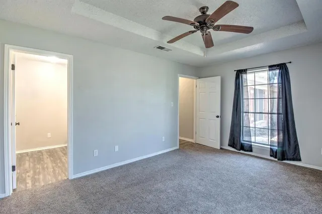an empty room with chandelier fan and windows