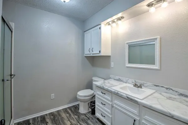 a bathroom with a granite countertop toilet sink and mirror