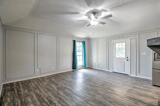 a view of an empty room with window and wooden floor