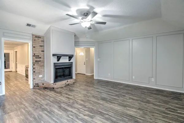 an empty room with wooden floor fireplace and windows