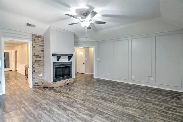 an empty room with wooden floor fireplace and windows
