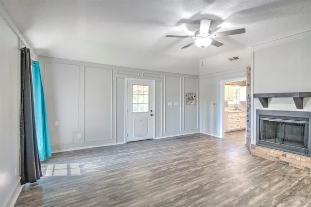 a view of an empty room with window and wooden floor