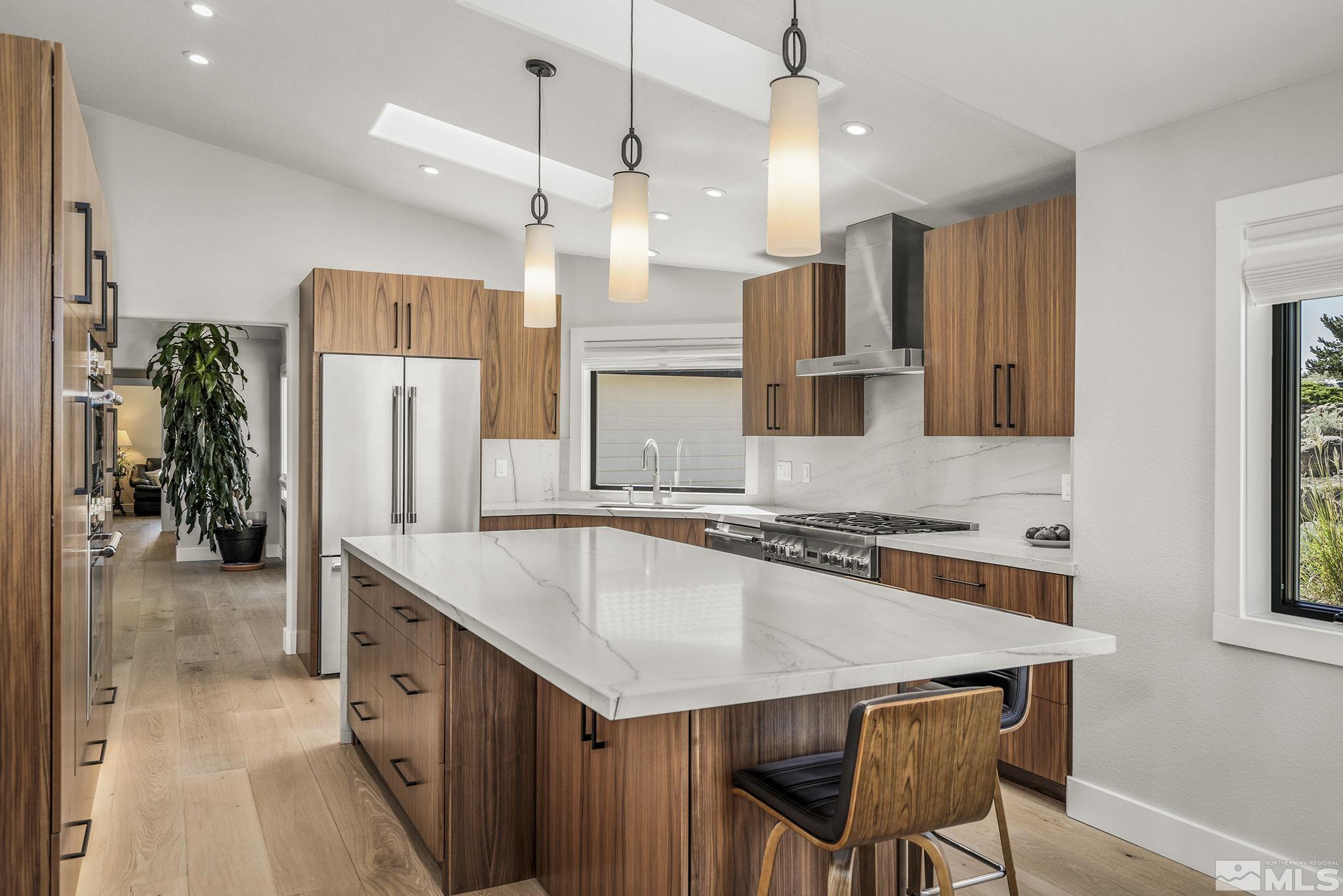 13285 Welcome Way Reno, NV 89511 - Photo 10 of 38 a kitchen with stainless steel appliances granite countertop a kitchen island a stove a refrigerator a sink a dining table and chairs with wooden floor