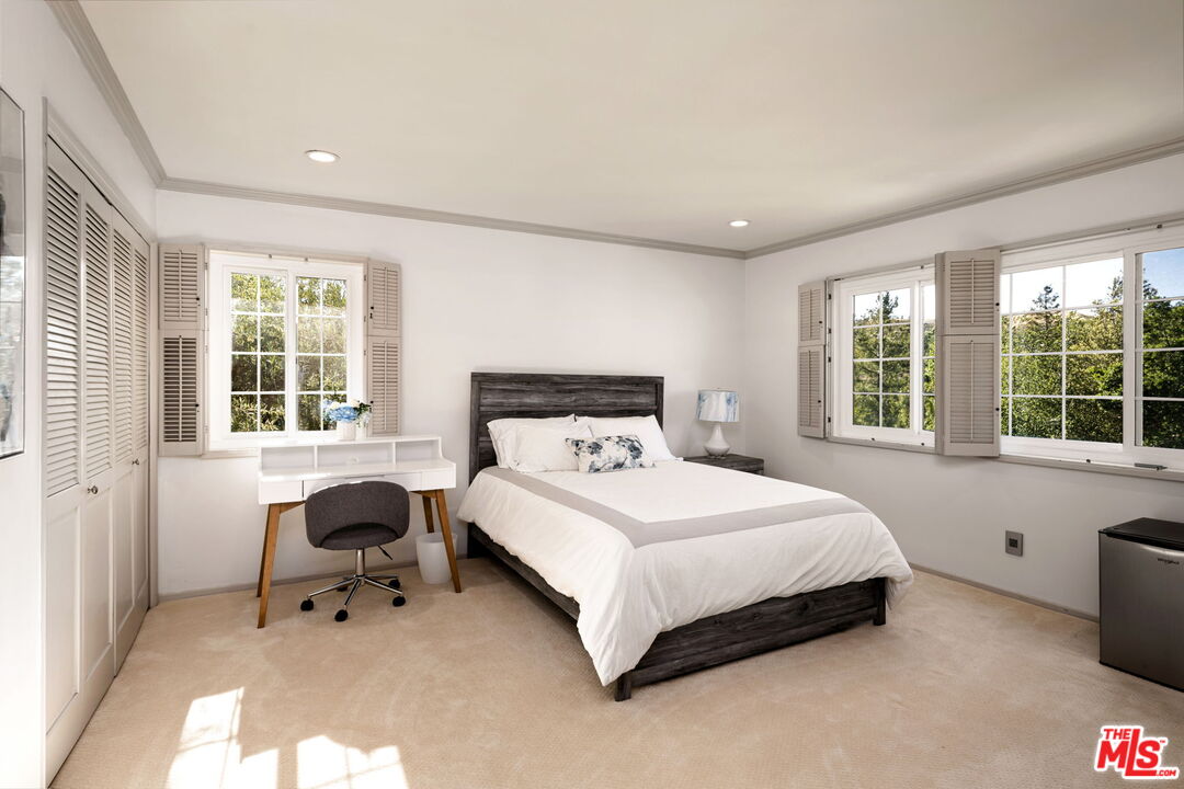 25021 Jim Bridger Road Hidden Hills, CA 91302 - Photo 18 of 30 a bedroom with a bed and a table in it with wooden floor