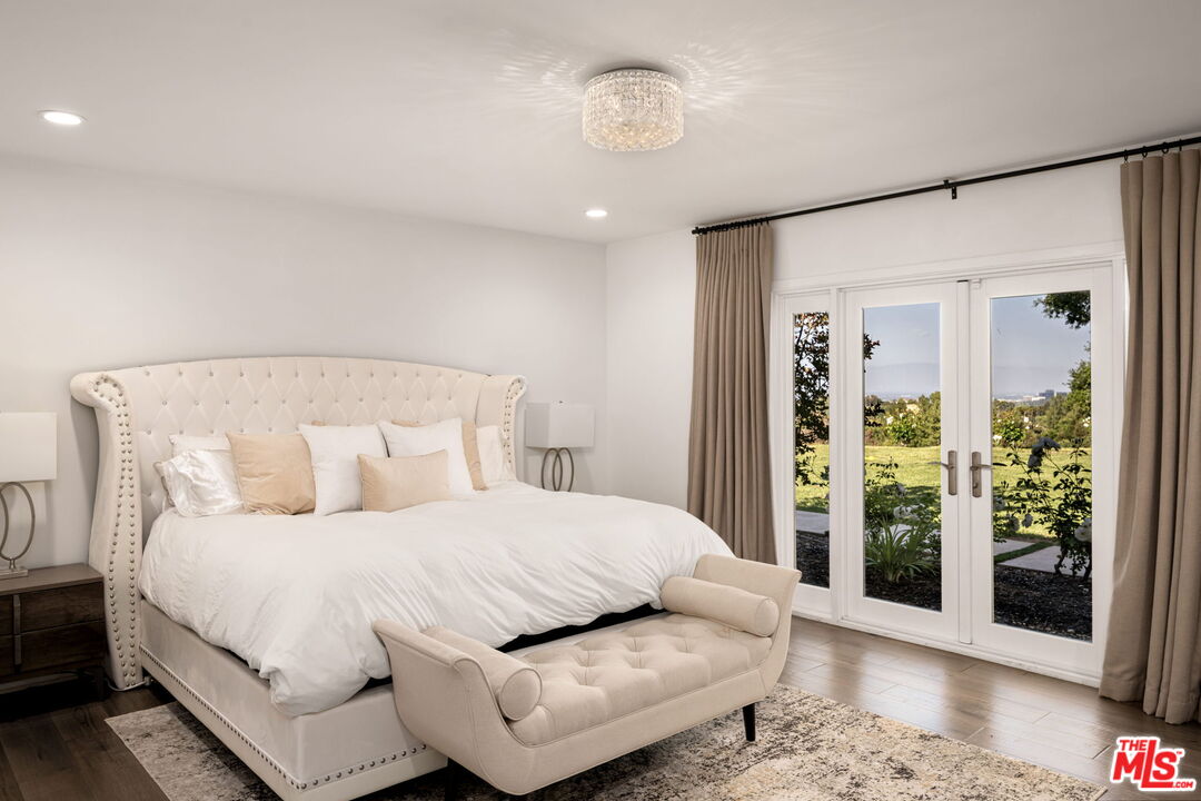 25021 Jim Bridger Road Hidden Hills, CA 91302 - Photo 7 of 30 a bedroom with a large bed and a chandelier