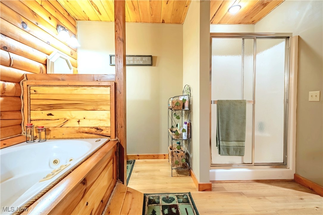 49144 Hickman Road Calcutta, OH 43920 - Photo 14 of 23 Bathroom with shower with separate bathtub, hardwood / wood-style floors, and rustic walls