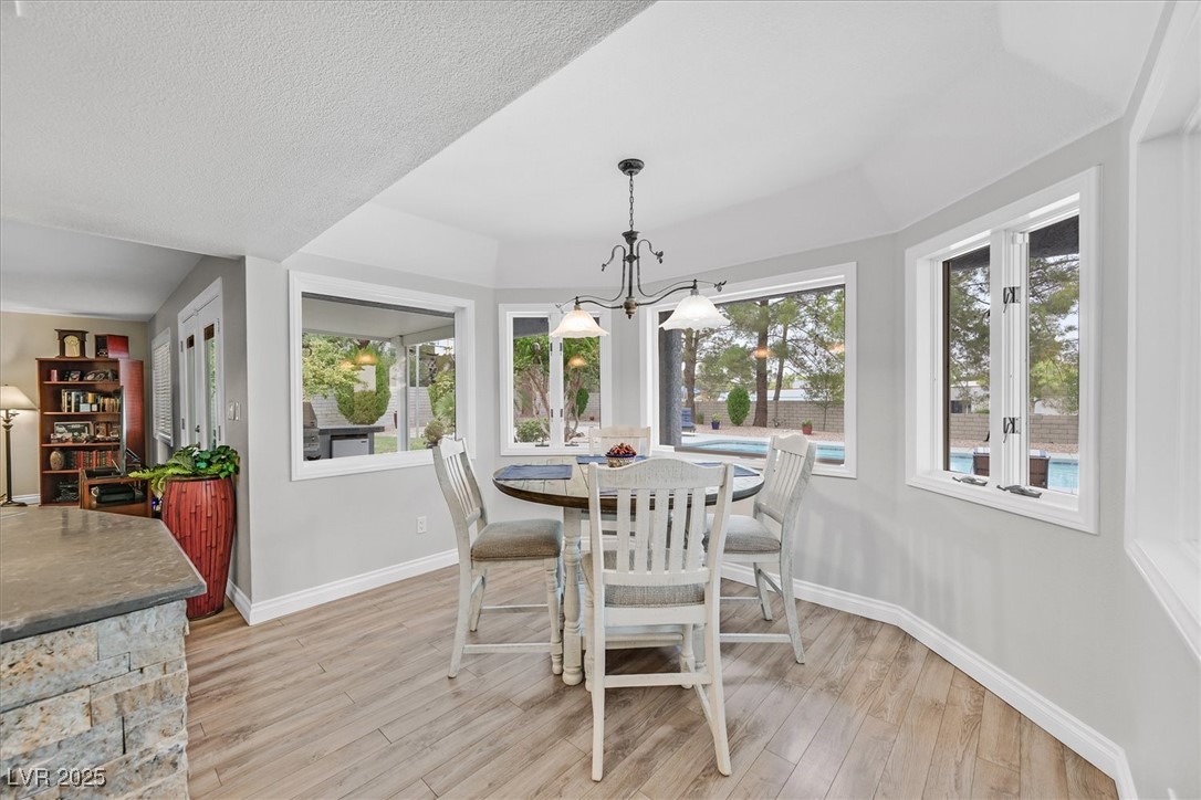 18 Hummingbird Circle Henderson, NV 89014 - Photo 12 of 39 Dining room featuring light wood-type flooring, a chandelier, and a textured ceiling