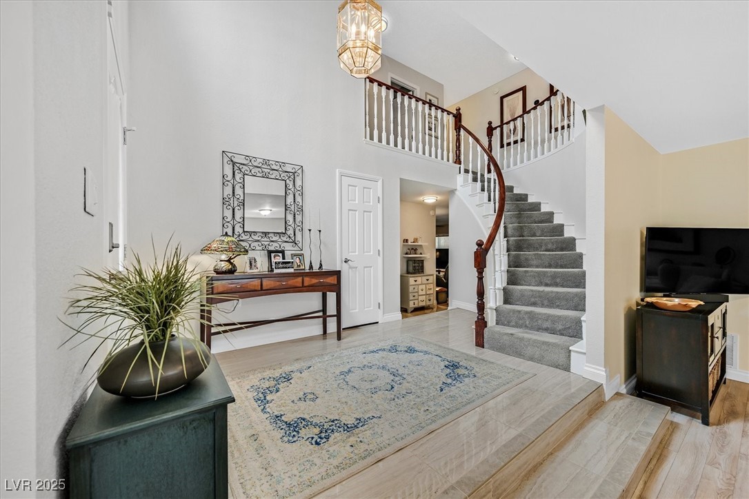 18 Hummingbird Circle Henderson, NV 89014 - Photo 15 of 39 Foyer entrance with stairway, a towering ceiling, light wood-style flooring, and a chandelier